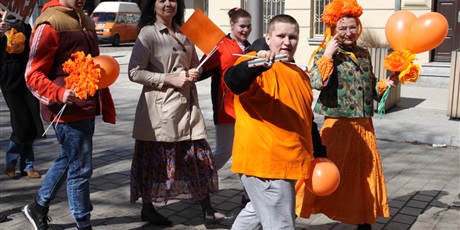 Powiększ grafikę: Uczniowie machają do fotografa pomarańczowymi balonami