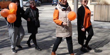 Powiększ grafikę: Uczniowie i nauczyciele machają do fotografa pomarańczowymi balonami