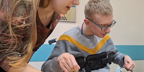 Powiększ grafikę: Niepełnosprawny uczeń układający dobierankę, w tle prace plastyczne na ścianie