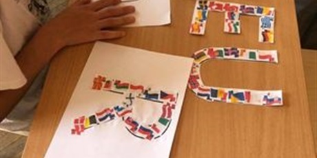 Powiększ grafikę: 1.	uczeń wykleja szablon litery O flagami krajów europejskich, na ławce leżą wyklejone już litery E, U i R.