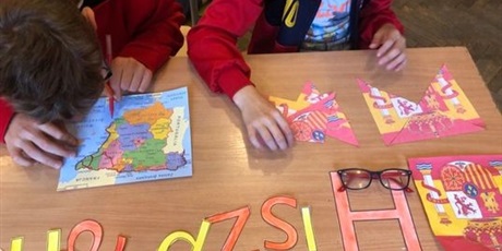 Powiększ grafikę: 4.	uczniowie pracują przy ławce: jeden układa herb Hiszpanii z rozsypanki, drugi odrysowuje kształt Hiszpanii na mapie.