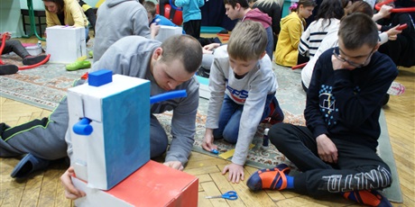 Powiększ grafikę: Trzej chłopcy siedzą na podłodze budują robota z kartonu