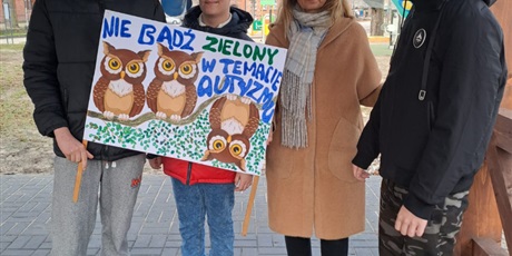 Powiększ grafikę: Uczniowie z nauczycielem trzymają plakat Nie bądź Zielony w Temacie Autyzmu, w tle łąka przed Ośrodkiem