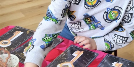 Powiększ grafikę: Chłopiec siedzi przy stoliku I sprawdza w lusterkach ,kim będzie w przyszłości