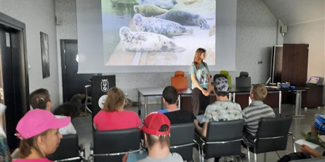 Powiększ grafikę: Uczniowie oglądają na dużym ekranie prezentację o morskich gatunkach ssaków.