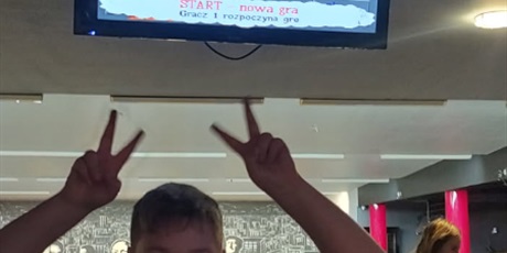 Powiększ grafikę: Radość dziecka ze zdobycia punktów, w tle tablica wyników.