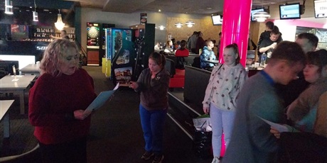 Powiększ grafikę: Wręczenie nagród za udział w bowlingu, w tle boxy dla zawodników.