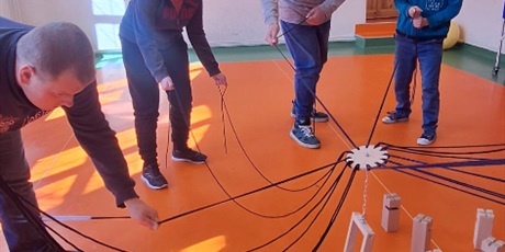 Powiększ grafikę: Uczniowie umiętnie ciągną za sznurki, by postawić wieżę.