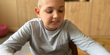 Powiększ grafikę: Chlopiec siedzi przy stoliku a przed nim na talerzu leży muffinka bananowo -czekoladowa.