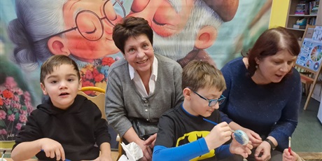 Powiększ grafikę: 7.	Babcie z wnukami siedzą przy stoliku I malują świeczniki. 