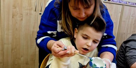 Powiększ grafikę: 4.	Chłopiec z mamą malują świecznik przy stoliku.