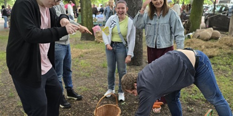 Powiększ grafikę: Uśmiechnięta młodzież zbiera warzywa. Wokół teren zielony.