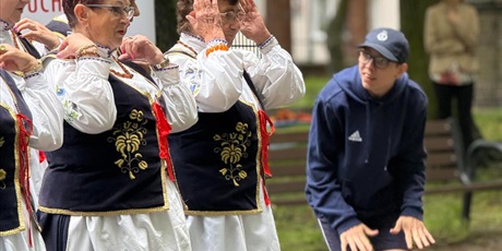 Powiększ grafikę: Kobiety w kaszubskich strojach. Nastolatek w stroju sportowym. W tle zieleń.