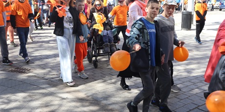 Powiększ grafikę: Wielu uczniów w barwach pomarańczowych przemieszczają się na pochodzie.