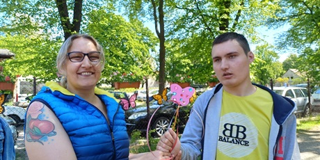 Powiększ grafikę: Chłopiec z mamą z czarodziejską różdżką, w tle drzewa i samochody