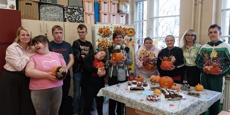 Powiększ grafikę: 8 uczniow i 2 nauczycielki pozują do zdjęcia, uczniowie trzymają udekorowane przez siebie dynie.