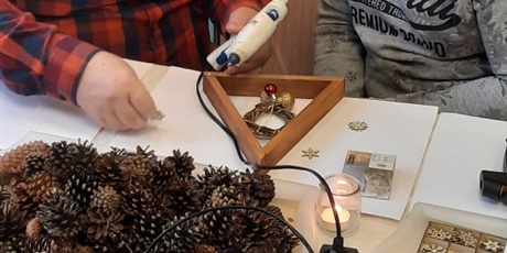 Powiększ grafikę: ojciec z synem tworzą stroik korzystając z elementów drewnianych i kleju na gorąco