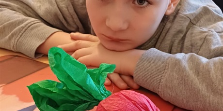 Powiększ grafikę: Chłopiec oparty o stół patrzy na buraka przestrzennego zrobionego z bibuły, który leży na stole.