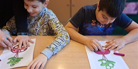 Powiększ grafikę: Dwóch chłopców przy ławce wylepia luki w buraczkach plasteliną.