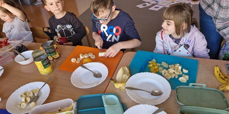 Powiększ grafikę: 8.	Dzieci siedzą przy stoliku I kroją owoce.