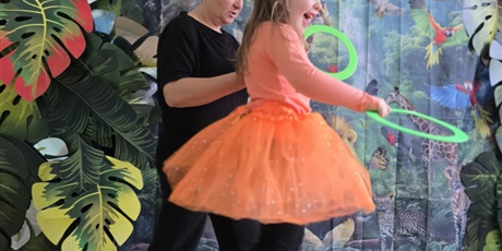 Powiększ grafikę: Wychowanka i nauczyciel rzucają kółkami do celu. W tle dekroacja.