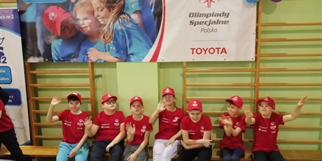 Powiększ grafikę: Wszyscy nasi młodzi sportowcy: Wiktoria, Andrzej, Roman, Seweryn, Bartek, Maciek i Adam, przebrani w czerwone koszulki i czapeczki, czekają na rozpoczęcie imprezy.