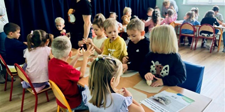 Powiększ grafikę: 7.	Dzieci siedzą wokół ścieżki sensorycznej przed nimi siedzi nauczycielka.