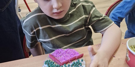 Powiększ grafikę: 1.	Chłopiec wypełnia tekturowe jajko materiałami sypkimi t.j. ryż i cieciorka.