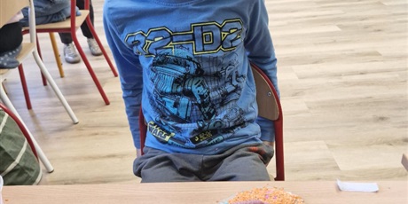 Powiększ grafikę: 6.	Chłopiec siedzi przy stoliku I przygotowują swoją pracę.