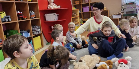 Powiększ grafikę: 5.	Chłopiec siedzi na podłodze a przed nim ułożone są misie