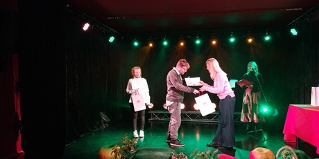 Powiększ grafikę: Kobieta wręcza nagrodę chłopcu, stoją na scenie.