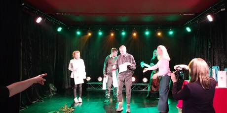 Powiększ grafikę: Na scenie stoi prowadząca galę z trójką nagrodzonych laureatów.