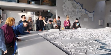 Powiększ grafikę: Stoja uczniowie i nauczyciele i przyglądaja się dużej makiecie przedstawiającej centrum Gdańska.