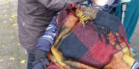 Powiększ grafikę: Nauczyciel przystawia do oczu chłopcu który jest na wózku inwalidzkim lornetkę.