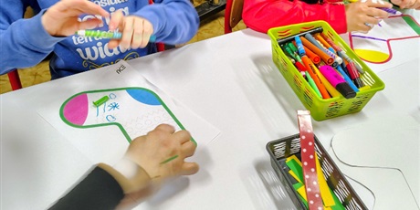 Powiększ grafikę: Zbliżenie na dwóch chłopców kolorująch mazakami szablony skarpet.