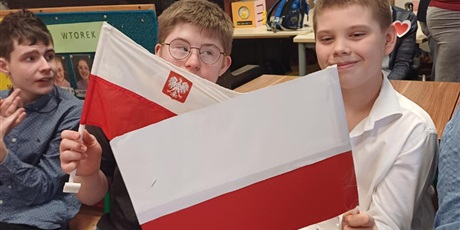 Powiększ grafikę: Chłopcy z biało-czerwonymi flagami na widowni. W tle widownia