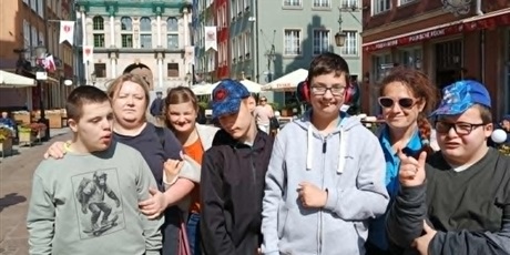 Powiększ grafikę: Grupa chłopców, dziewczynka i dwie kobiety stoja na ulicy. W tle Złota Brama w Gdańsku