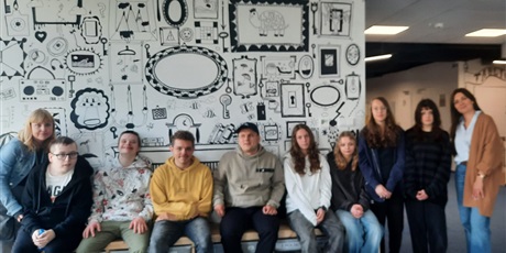 Powiększ grafikę: Uczniowie i uczennice wraz z nauczycielkami pozują do wspólnego zdjęcia na tle ściany ozdobionej czarno - białym graffiti