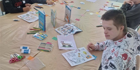 Powiększ grafikę: Sześcioro uczniów siedzi za stołem konferencyjnym i ogląda prelekcję na ekranie projekcyjnym.